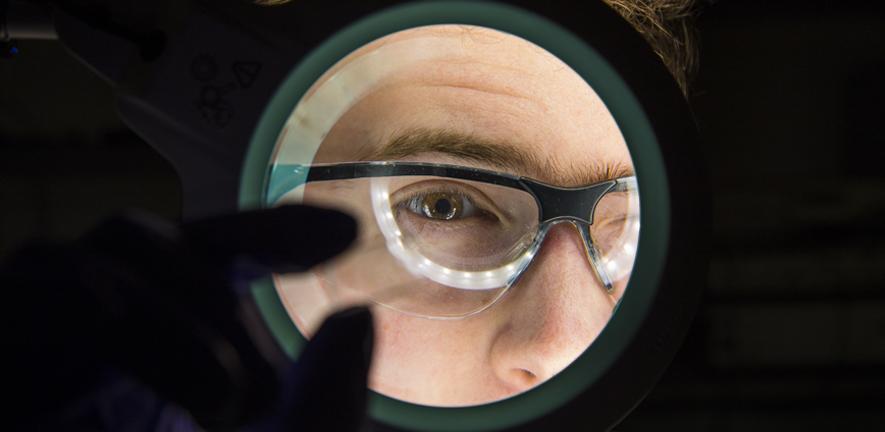 A scientist viewing a microfluidic chip. A scientist viewing a microfluidic chip.